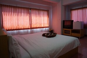 A hotel room with a bed, a TV, a small cabinet, and a window with curtains. - Premier Hotel Nakhonsithammarat (Nakhon Si Thammarat)