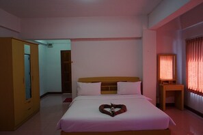 A hotel room with a bed, a wooden wardrobe, a desk with a lamp, and a window with curtains. - Premier Hotel Nakhonsithammarat (Nakhon Si Thammarat)