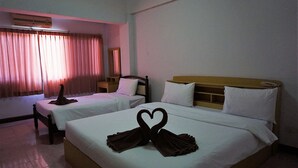 A hotel room with two beds, a window with curtains, an air conditioning unit, and a bedside table. - Premier Hotel Nakhonsithammarat (Nakhon Si Thammarat)