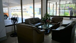 A modern room with leather sofas, a glass coffee table, and a standing fan. - Premier Hotel Nakhonsithammarat (Nakhon Si Thammarat)