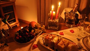 A dining table set with plates of food, a bottle of champagne, and candles.