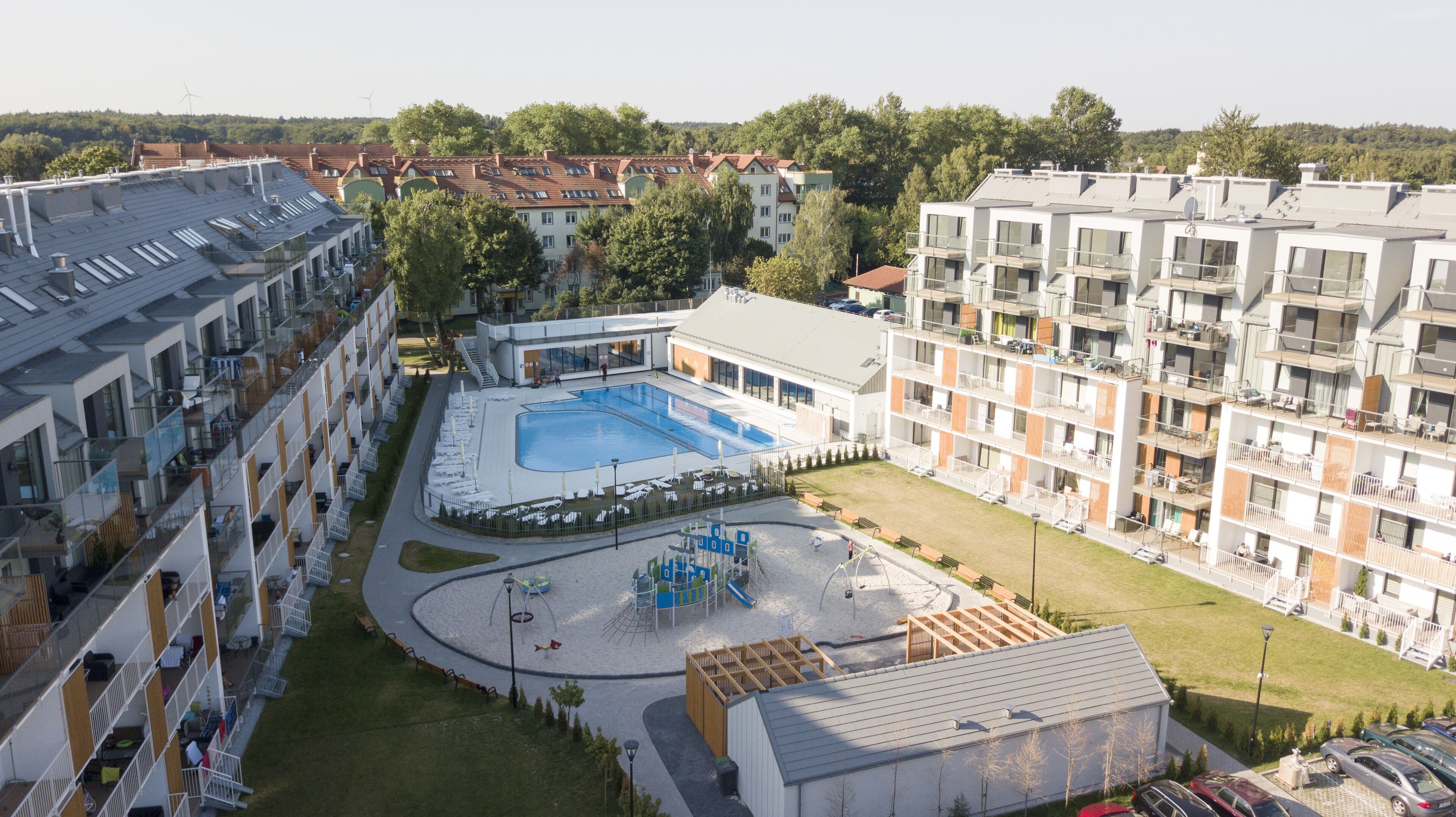 Un edificio residencial con piscina, varios balcones y una zona de juegos.