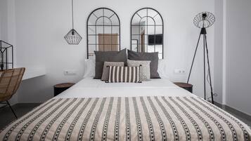 A modern bedroom with a large bed, two nightstands, a floor lamp, and a chair.