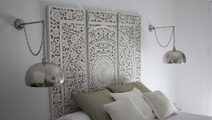 Un dormitorio con una cama, un cabecero decorativo y dos lámparas de pared.
