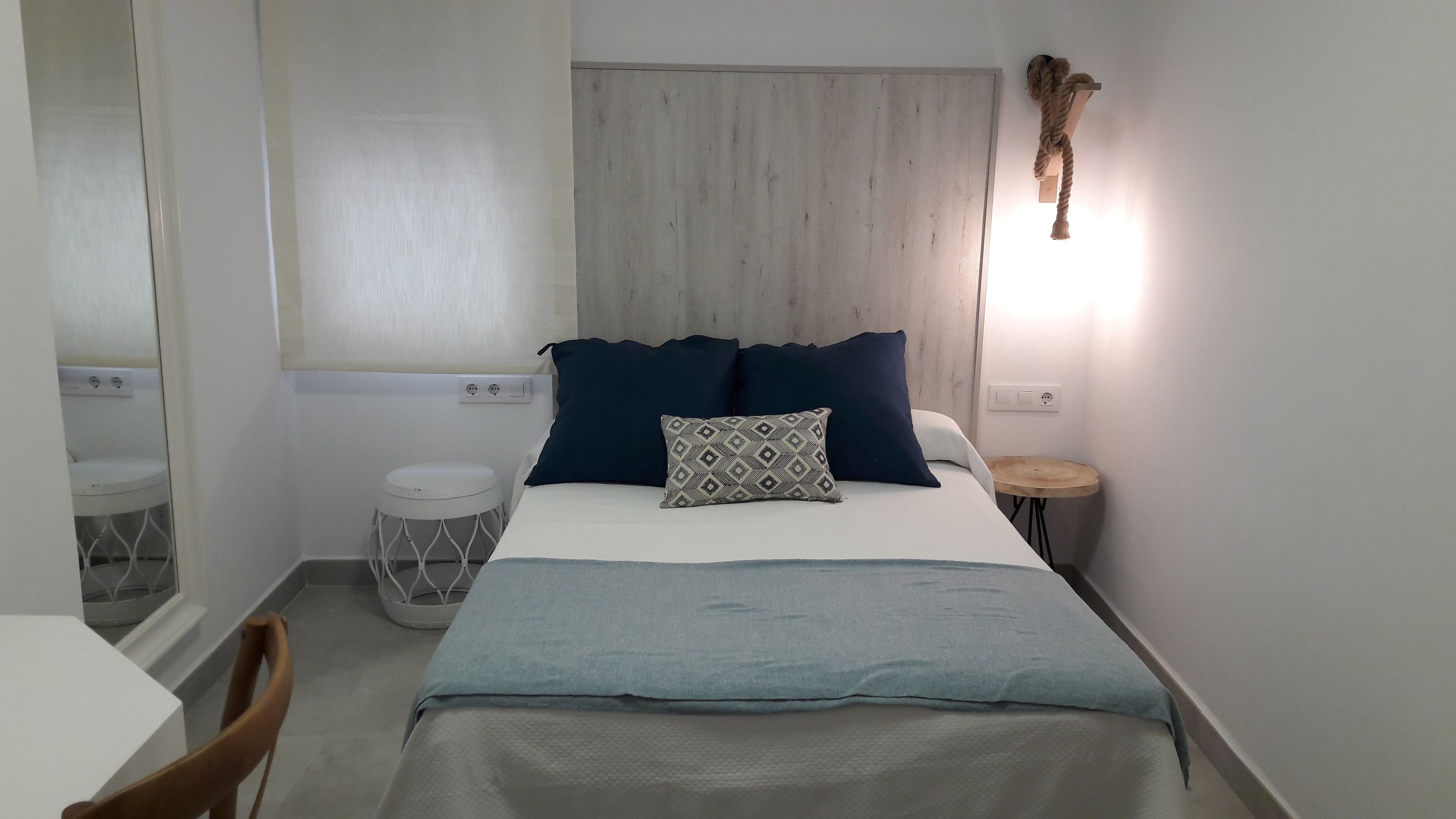 Un dormitorio con cama, mesita de noche y una pequeña mesa redonda.