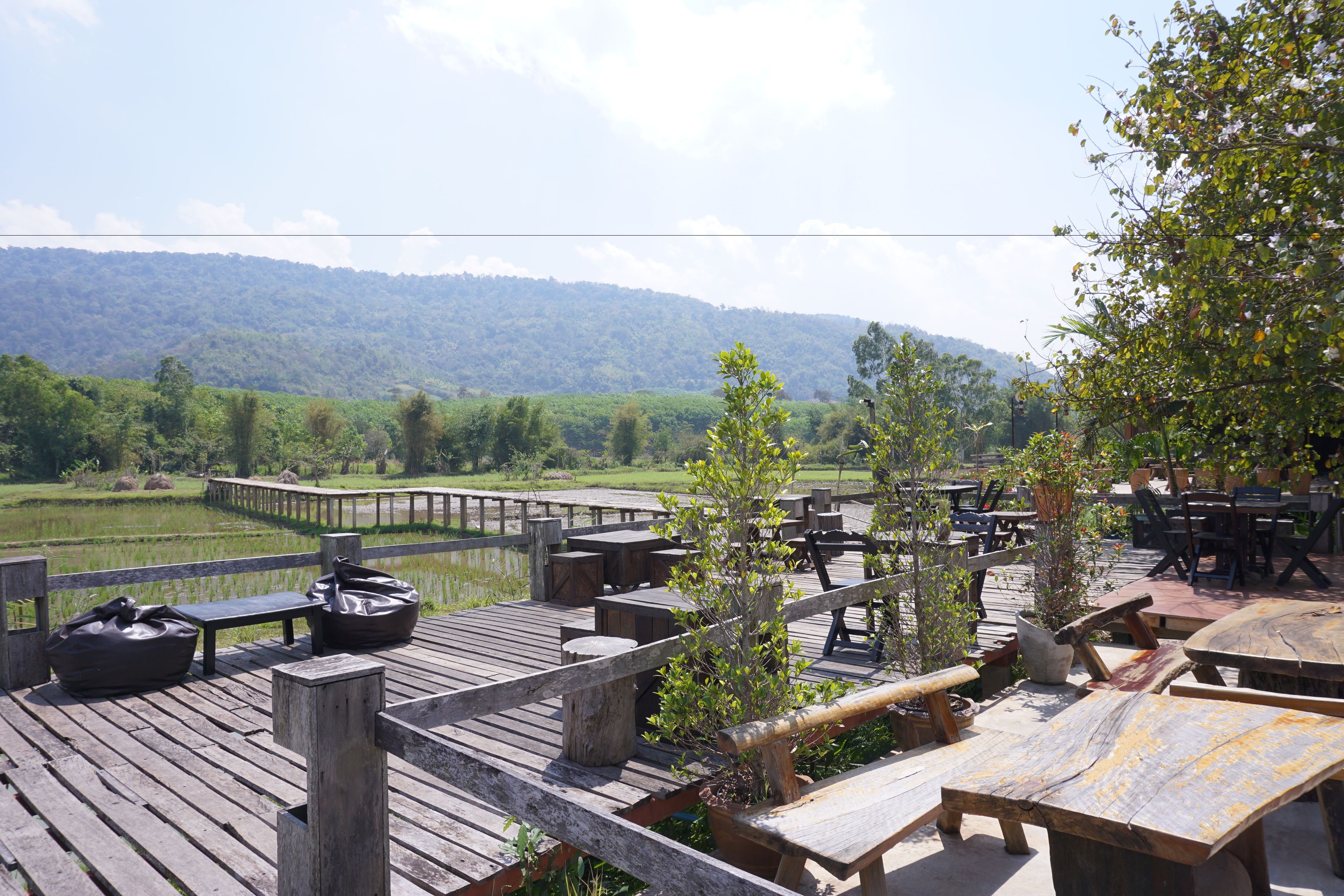 A wooden deck with outdoor seating, overlooking a lush green landscape and a body of water.