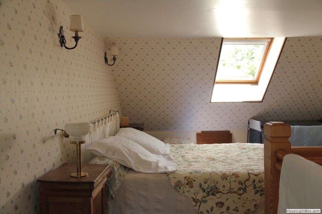 Ein Schlafzimmer mit einem Einzelbett, einem Nachttisch, einer Lampe, einem Fenster und einer Heizung.