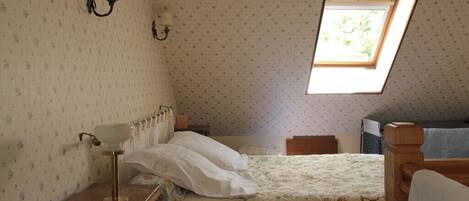 A bedroom with a single bed, a nightstand, a lamp, a window, and a radiator.