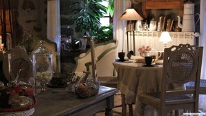 A cozy dining area with a table set for two, surrounded by bookshelves and a potted plant.