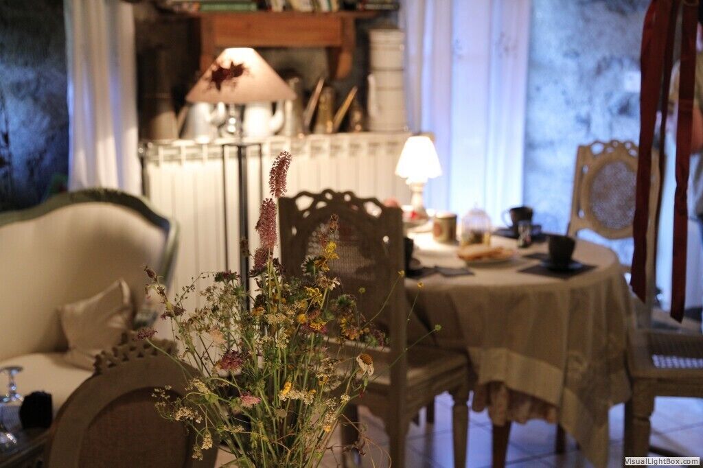 Een eetgedeelte met een tafel gedekt voor twee personen, een bloevas en een lamp op de tafel.