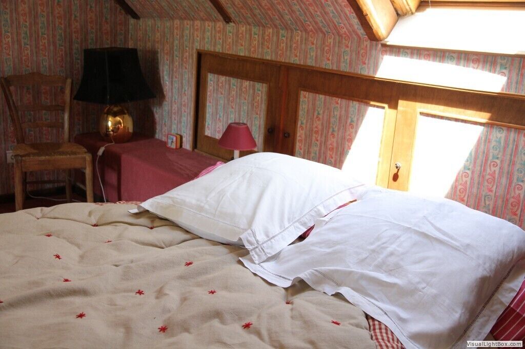 Une chambre à coucher avec un lit, une chaise, une table et une lampe.