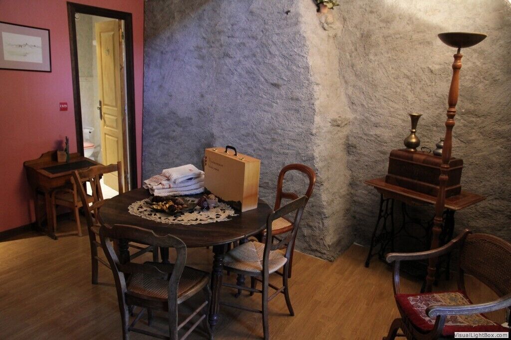 A dining area with a round wooden table, four chairs, a small wooden side table, and a vintage lamp.