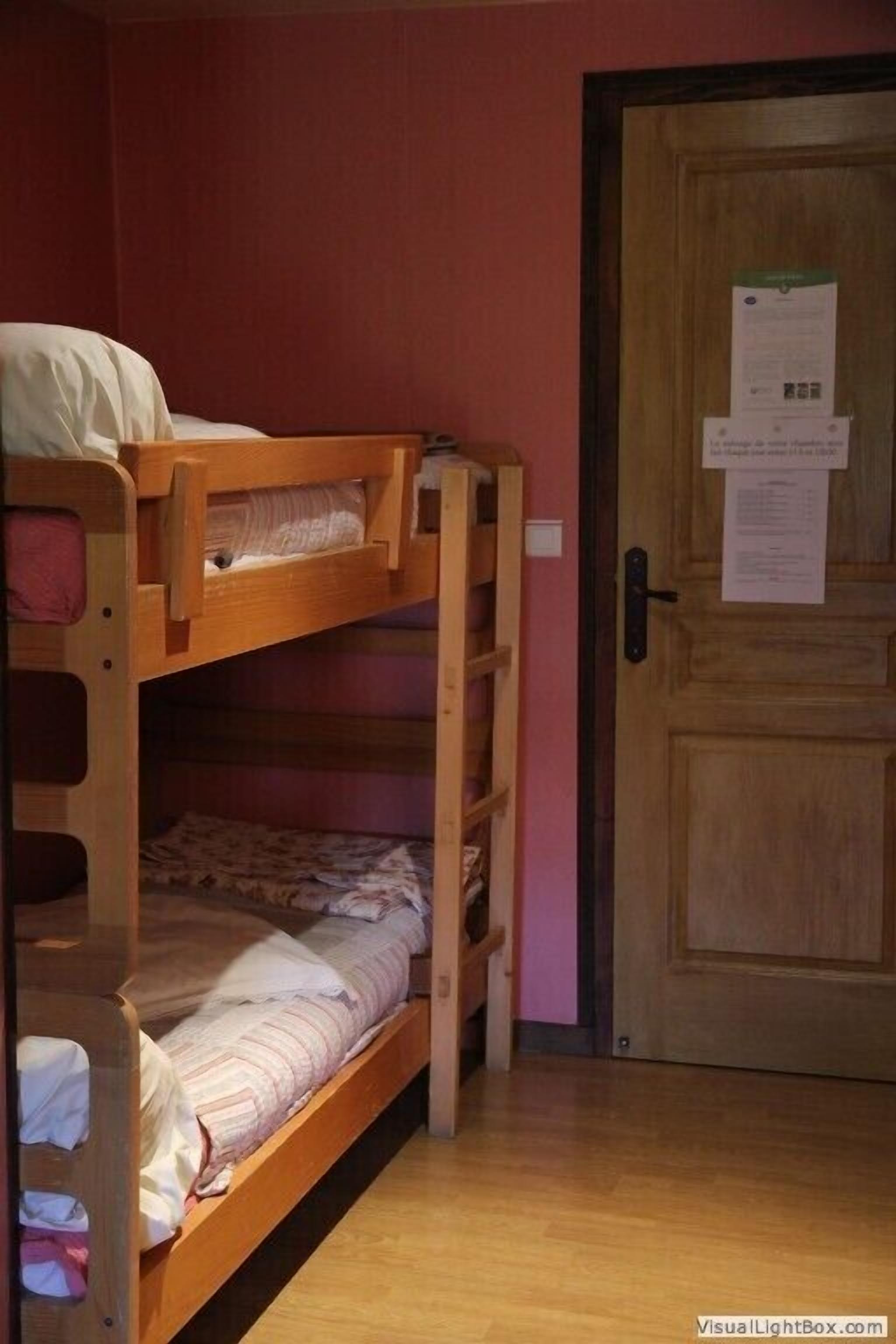 A bunk bed room with a wooden door and a notice on it.