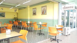 L’intérieur d’un restaurant avec des murs jaunes, des chaises orange et des tables.