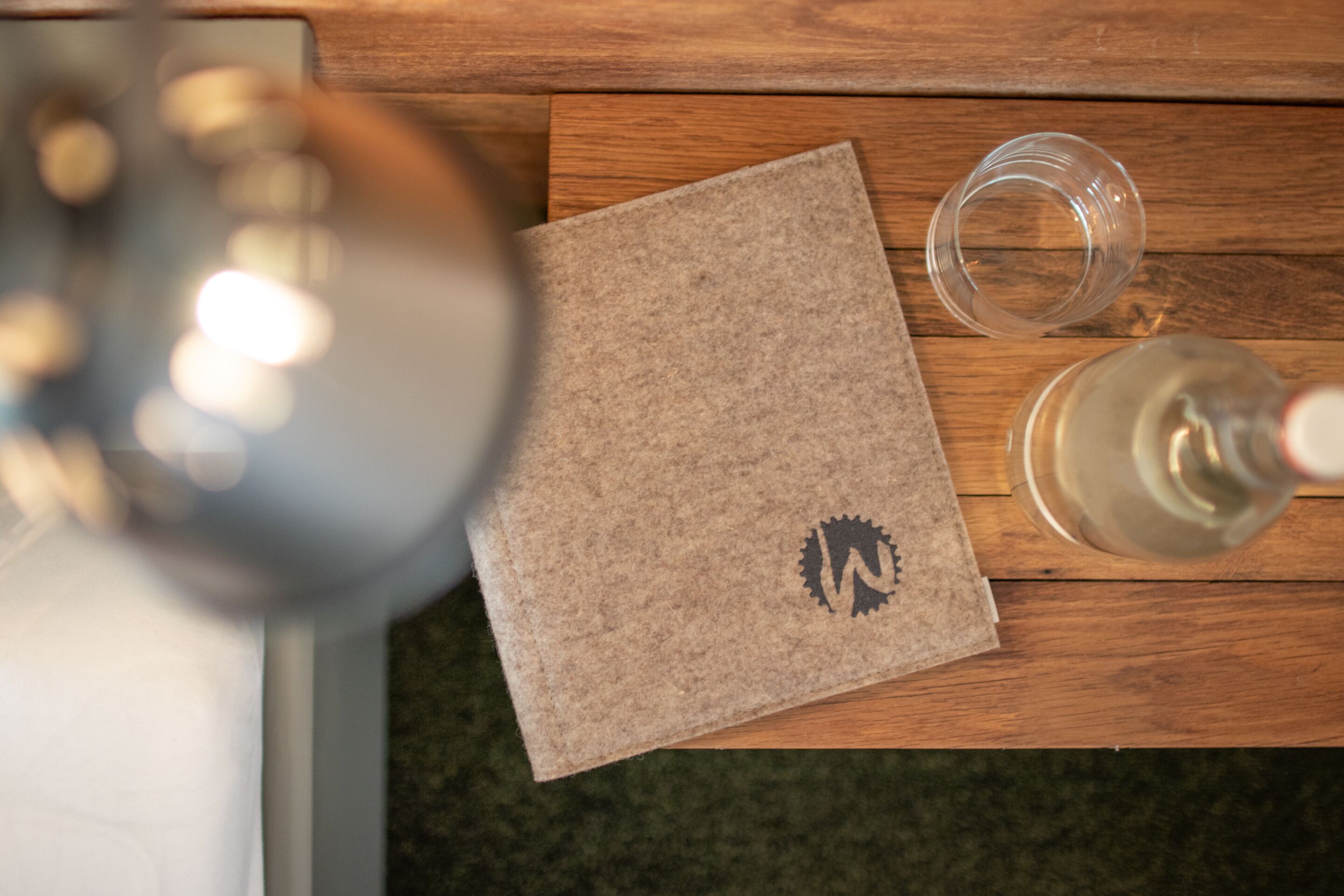 Ein Holztisch mit einer braunen Papiertüte, einer klaren Glasflasche und einem Glas mit weißer Flüssigkeit.