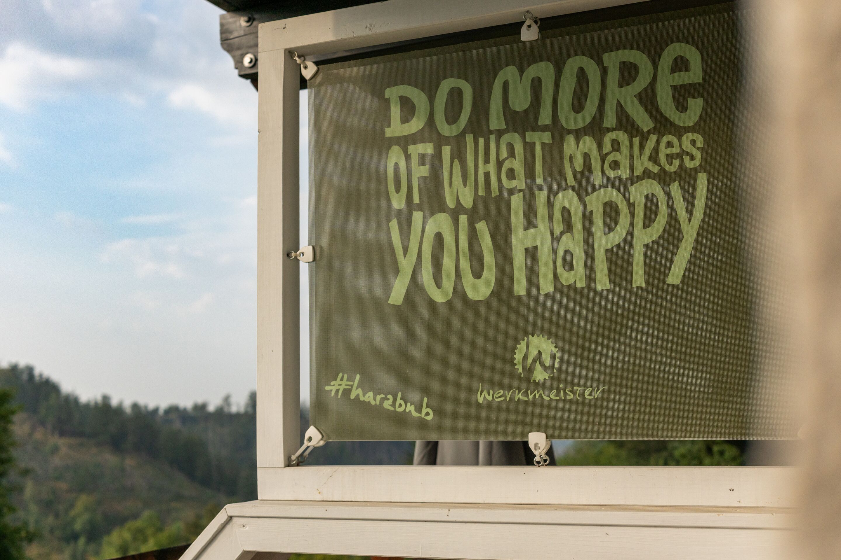 A motivational sign with the text "DO MORE OF WHAT MAKES YOU HAPPY" and hashtags "#sharebnb #werkmeister".