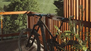 Un balcón de madera con una bicicleta, con vistas a un paisaje cubierto de hierba.