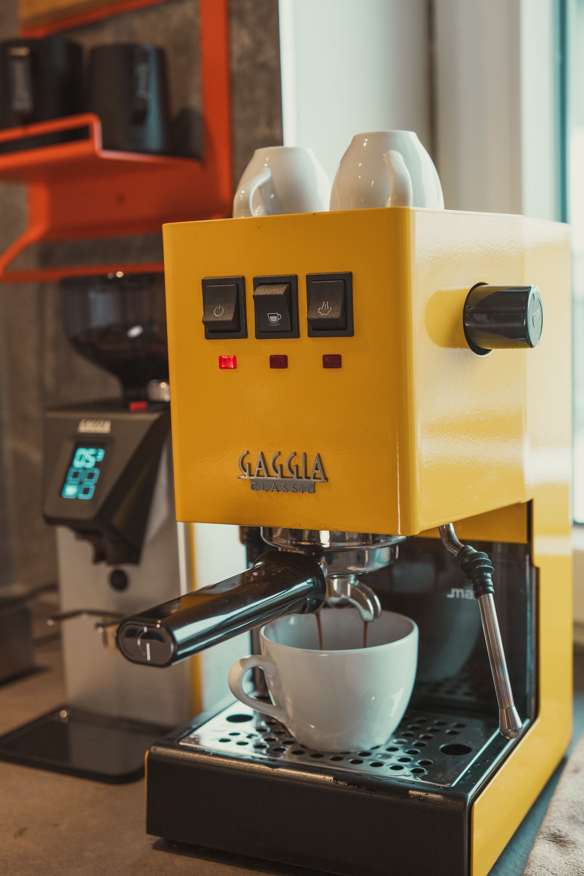Una máquina de espresso Gaggia amarilla con pantalla digital y una taza de café.