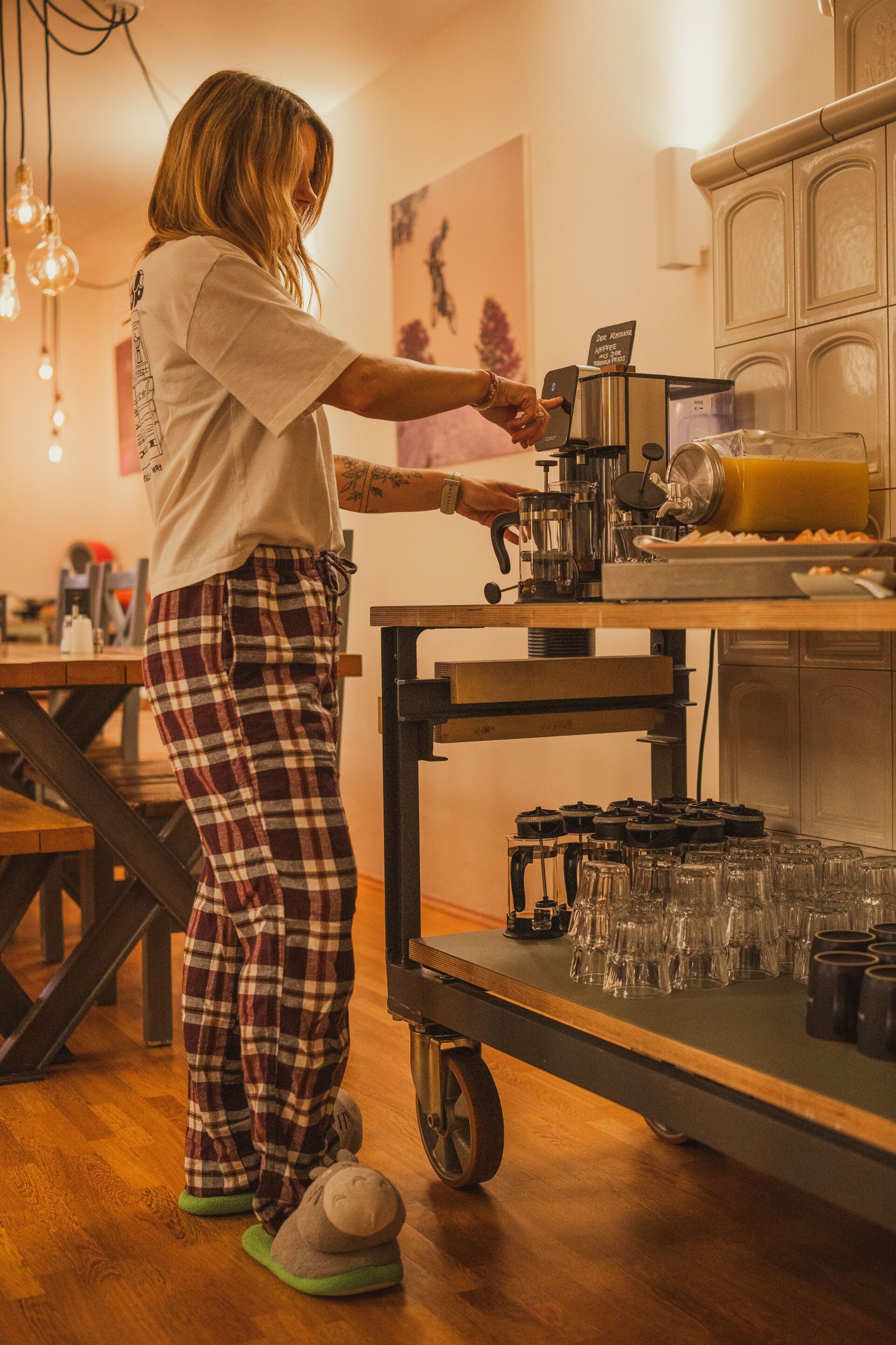 En person som gör i ordning kaffe vid en barista-station med en kaffemaskin, ett bricka med glas och en disk med en kaffekanna.