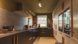 Una cocina moderna con armarios oscuros, horno empotrado y ventana con vistas a un balcón.