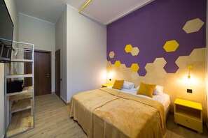 A bedroom with a bed, bedside tables, a wardrobe, and a wall with geometric patterns.