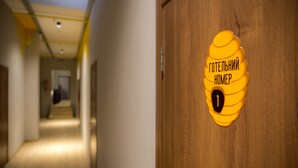 A hallway with a wooden door marked with a yellow honeycomb sign and the number 1. - Hotel Bee Station - Hostel (Kyiv)