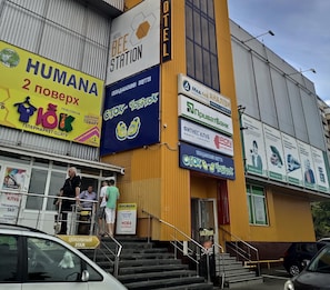 A building with multiple signs advertising various businesses, including a hotel, a supermarket, and a fitness club.