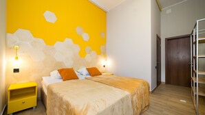 A bedroom with two beds, a wooden floor, a yellow wall with hexagonal patterns, and a wooden door. - Hotel Bee Station - Hostel (Kyiv)