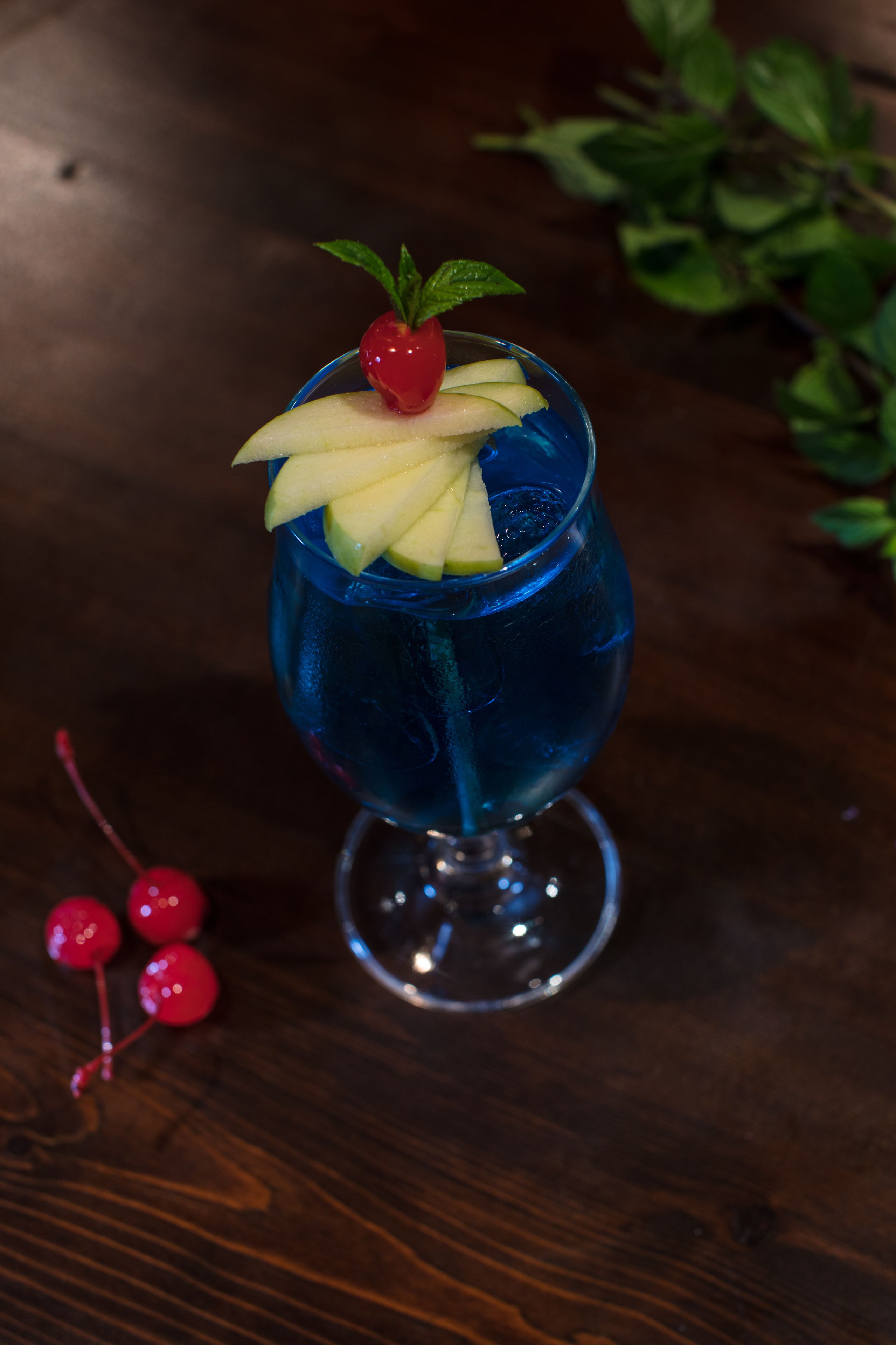 A cocktail in a tall glass with a cherry garnish.