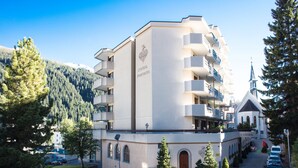 A multi-story hotel with a central courtyard, balconies, and a church in the background. - Central Apartments Davos (Davos)