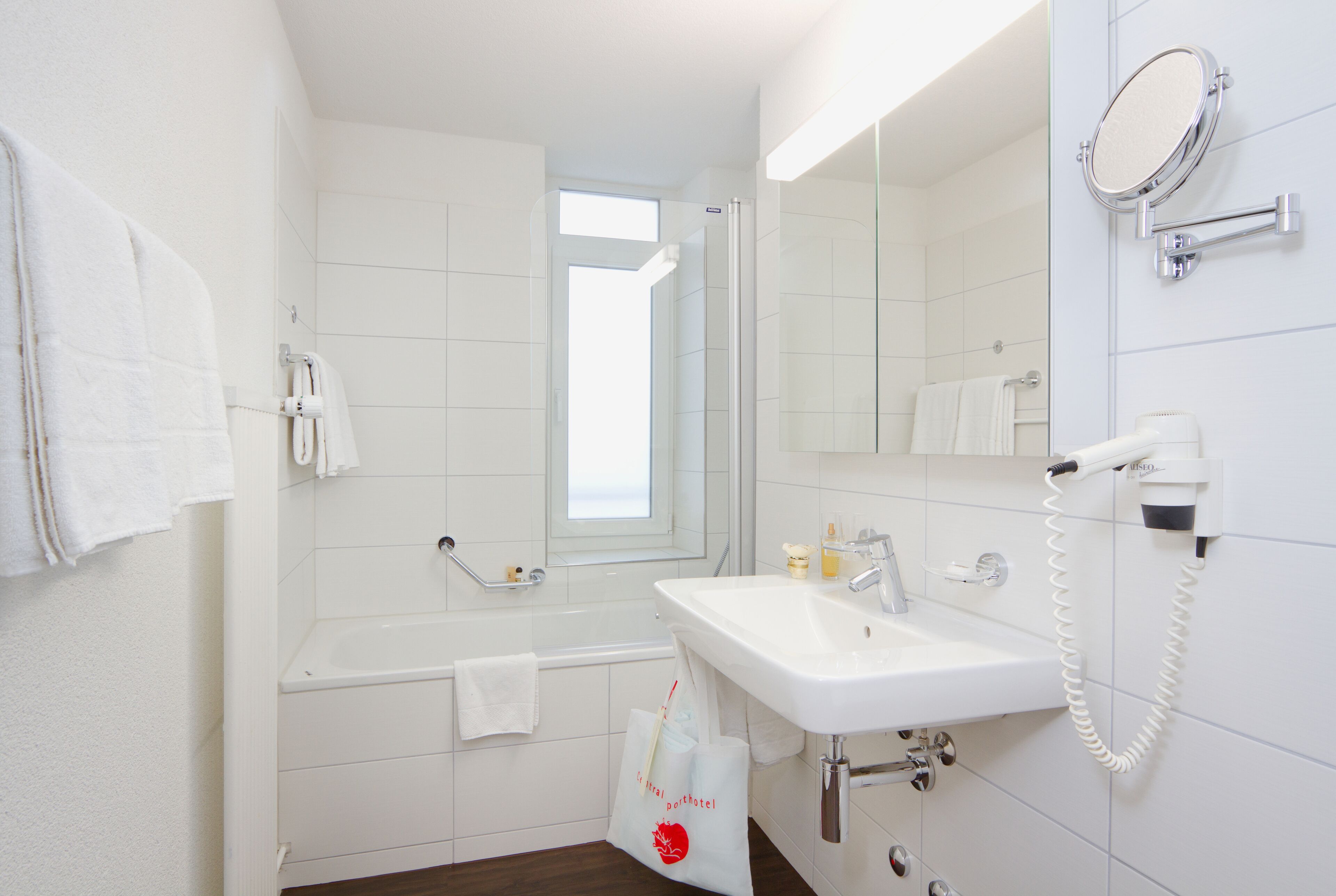 A bathroom with a white sink, a mirror, a handheld showerhead, and a towel rack.