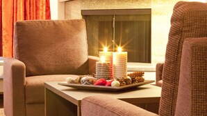 A cozy seating area with two brown upholstered chairs, a small wooden table, and a decorative tray with candles and pine cones. - Central Apartments Davos (Davos)