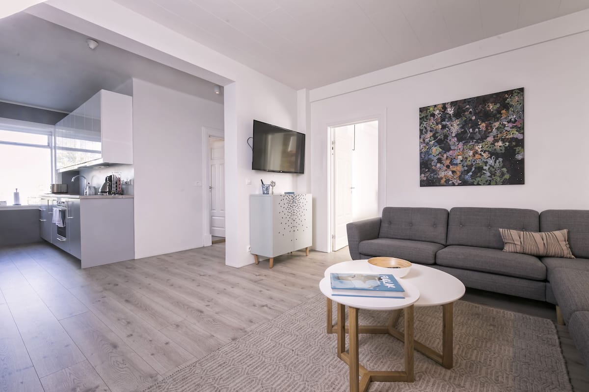 A modern living room with a grey sofa, a coffee table, and a TV mounted on the wall.