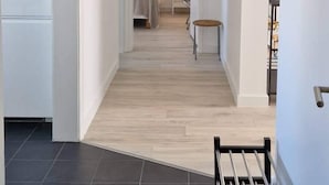 A hallway with a bench, a bed, and a nightstand with a lamp in the background. - Theater Row Apartments (Reykjavik)