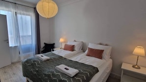 A hotel room with two beds, a desk, and a chair. - Theater Row Apartments (Reykjavik)