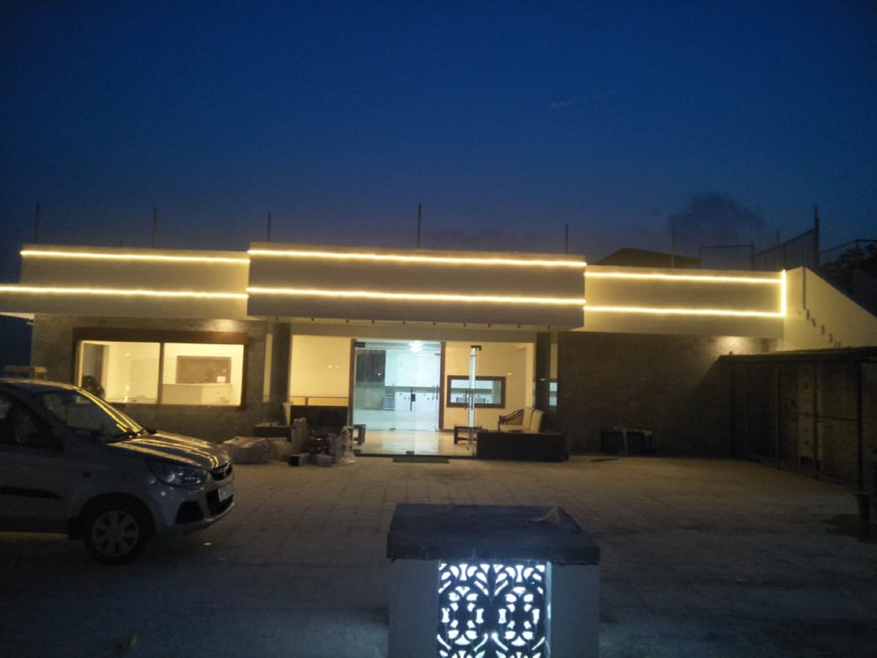 A modern building with a flat roof, large windows, and a car parked in front.