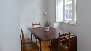 A dining area with a wooden table and chairs, a potted plant, and a lamp. - Carolina M Apartment (Porto)