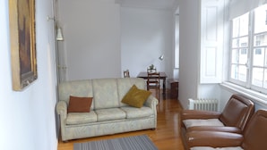 A living room with a sofa, a brown leather couch, a dining table with chairs, and a radiator. - Carolina M Apartment (Porto)