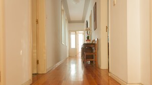 A hallway with wooden flooring, white walls, and a door at the end. - Carolina M Apartment (Porto)