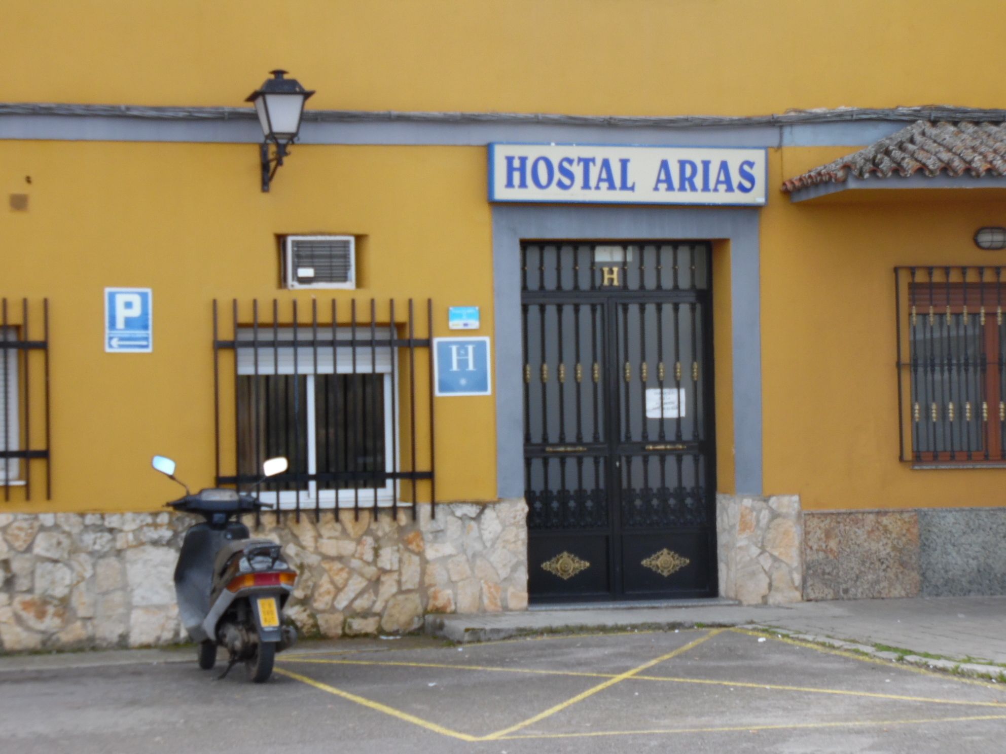Un edificio con un letrero que dice "HOSTAL ARIAS" y una motocicleta estacionada frente a él.