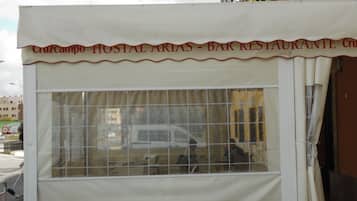 A small, enclosed outdoor structure with a window and a white awning.