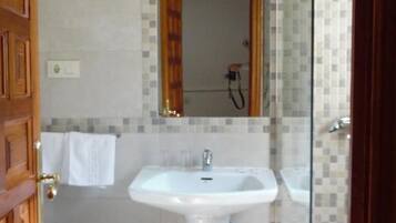Un baño con lavamanos blanco, inodoro y zona de ducha.