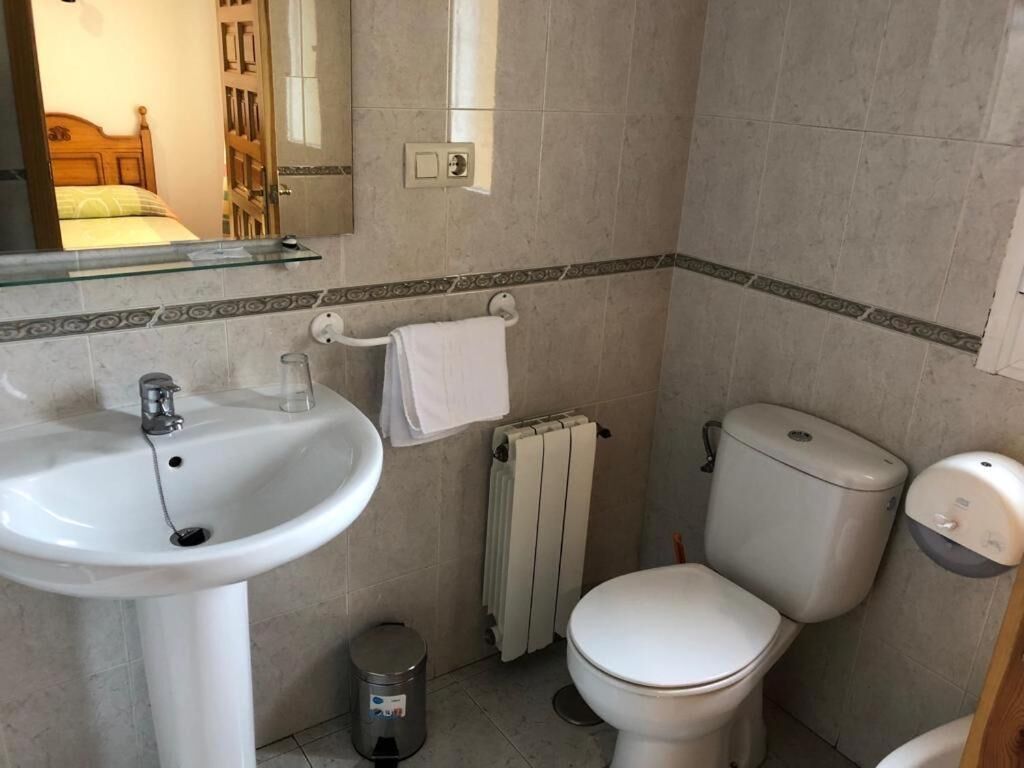 Un baño con lavamanos blanco, inodoro y radiador.