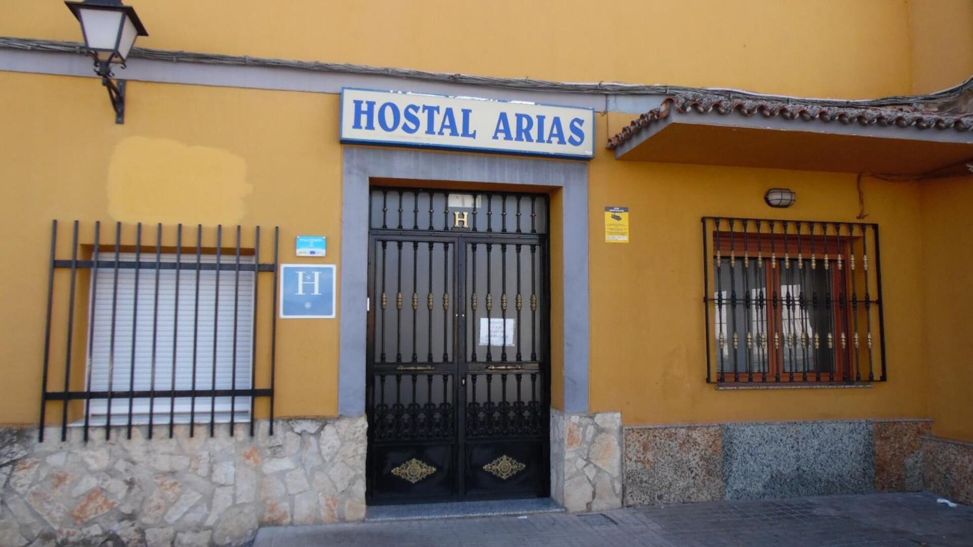 Un edificio con un letrero que dice "HOSTAL ARIAS" sobre un portón negro.