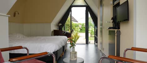 A bedroom with a bed, a desk, and a chair. There is a window with a view of the outside.