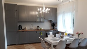 A modern kitchen with grey cabinets, a wooden countertop, and a dining area with a white table and grey chairs.