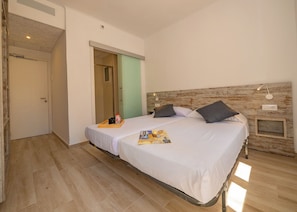 A double bed with a wooden headboard, a bedside table with a lamp, and a tray with a bottle and a cup on the bed. - AGI Gloria Rooms (Roses)