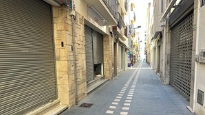 A narrow urban street with closed shop fronts and a pedestrian pathway. - AGI Gloria Rooms (Roses)