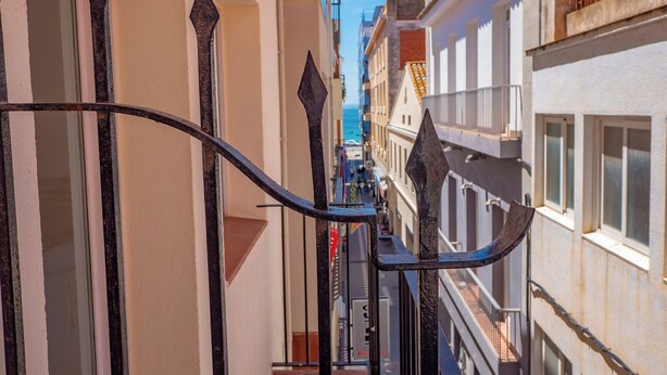 A narrow alleyway with a metal gate and buildings on either side. - AGI Gloria Rooms (Roses)