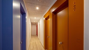 A corridor with doors on both sides, a wooden floor, and a ceiling with recessed lighting. - AGI Gloria Rooms (Roses)